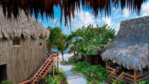 A thatched-roof building with a wooden staircase leading to a deck. - Ramon's Village Resort (San Pedro)