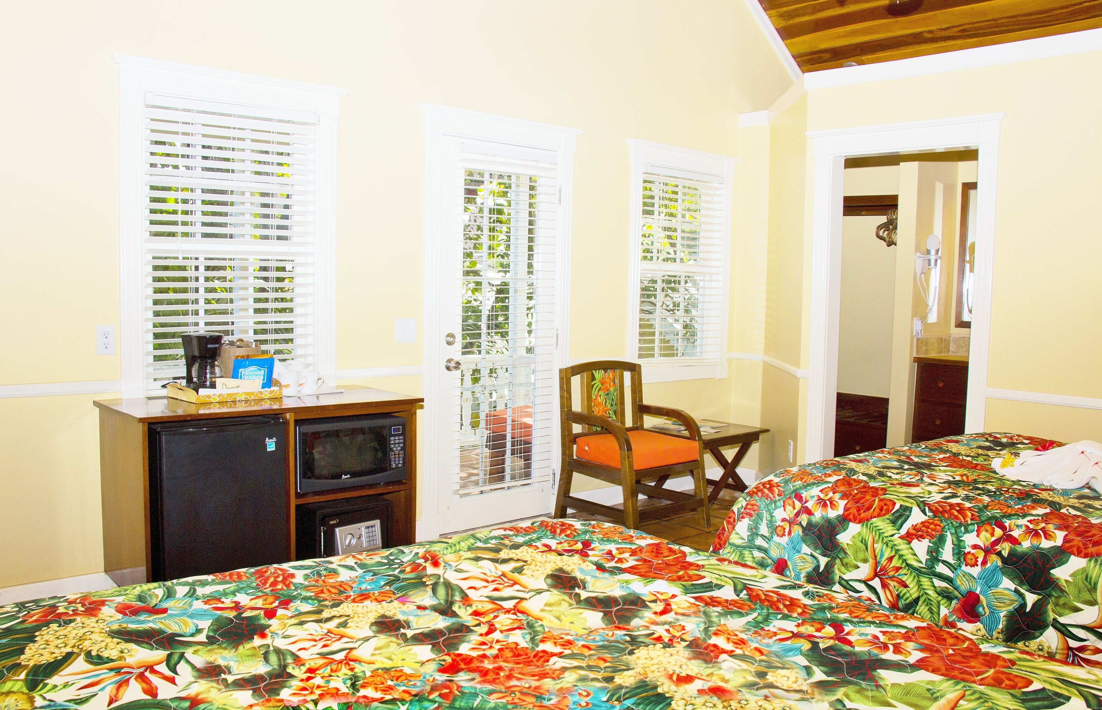Une chambre d’hôtel avec deux lits, une petite kitchenette et une chaise.