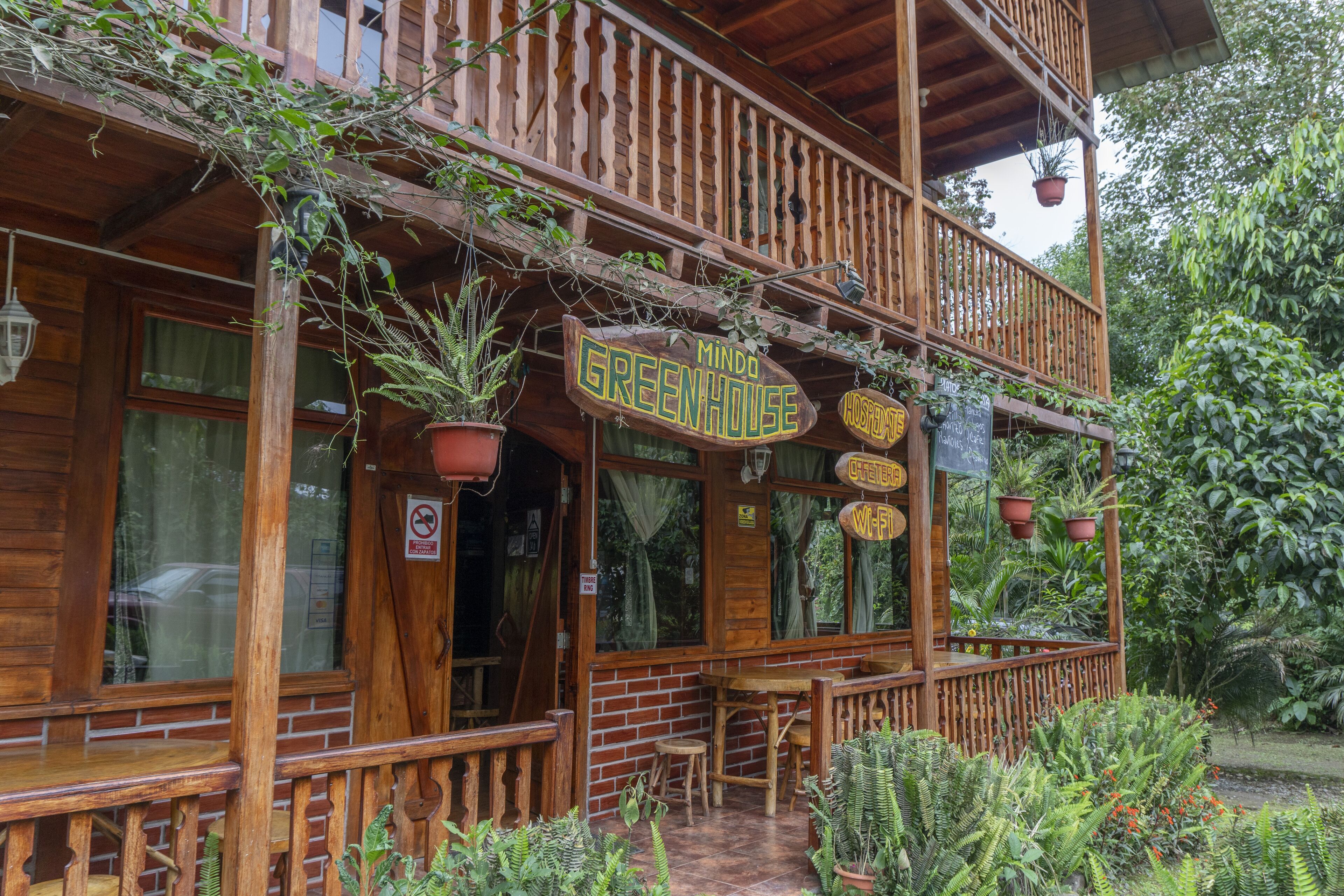Una construcción de madera con un letrero que dice "Mindo Greenhouse".