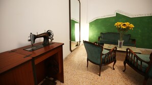 A room with a sewing machine, two chairs, a sofa, and a mirror. - Next Stop Roma Affittacamere Casilino (Rome)