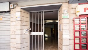 A building entrance with a metal gate, a red telephone booth, and a sign indicating the number 73. - Next Stop Roma Affittacamere Casilino (Rome)