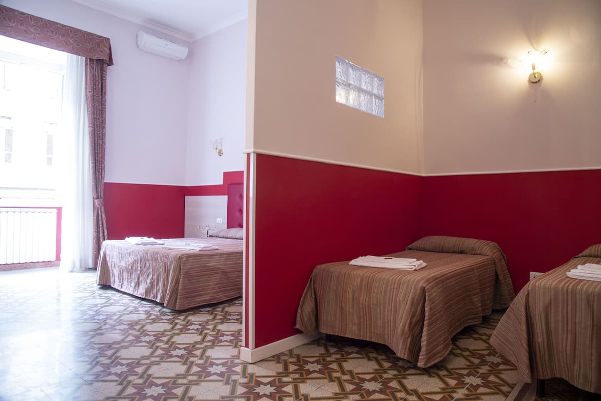A hotel room with two beds, a red accent wall, and patterned flooring.