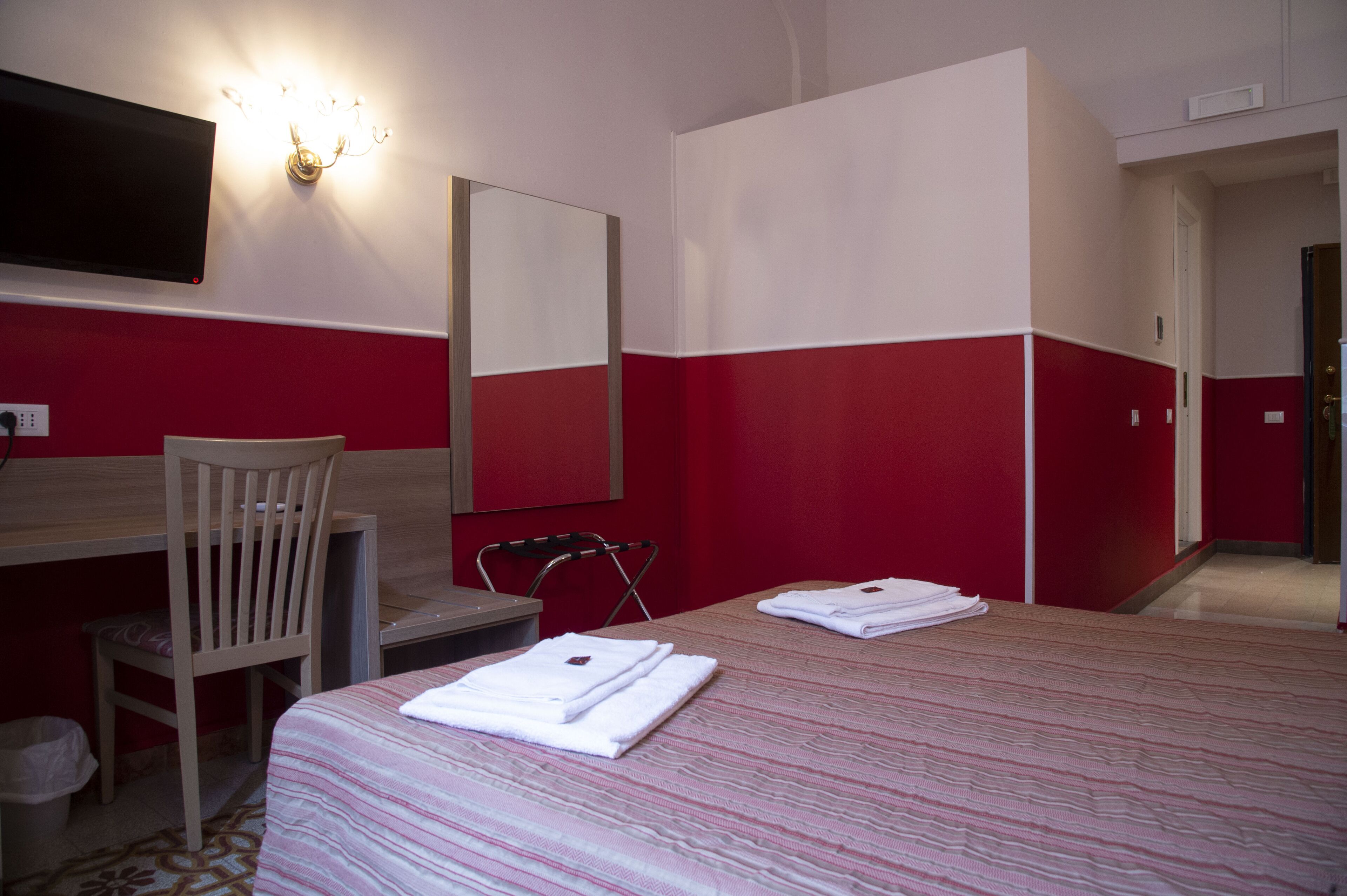 Ein Hotelzimmer mit zwei Betten, einem Schreibtisch, einem Stuhl und einem Fernseher.