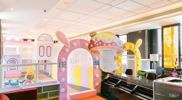Zona de juegos para niños con estructuras coloridas y un área de descanso con mesa y sillas.