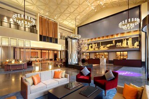 A spacious lobby with a high ceiling, a reception desk, seating areas, and a decorative tree centerpiece. - Four Points by Sheraton Chengdu, Anren (Chengdu)