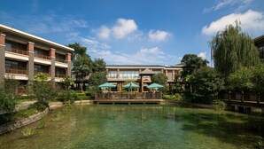 A hotel with a courtyard featuring a pond, outdoor seating with umbrellas, and a bridge. - Four Points by Sheraton Chengdu, Anren (Chengdu)