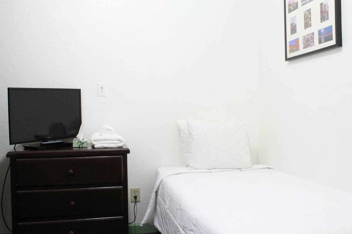 A hotel room with a bed, a dresser, a television, and a wall-mounted photo collage.