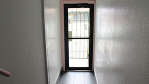 A narrow hallway with a door leading to a bright outdoor area. - Union Hotel (San Francisco)