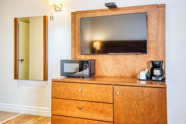 A wooden cabinet with a flat-screen TV, a microwave, and a coffee maker.
