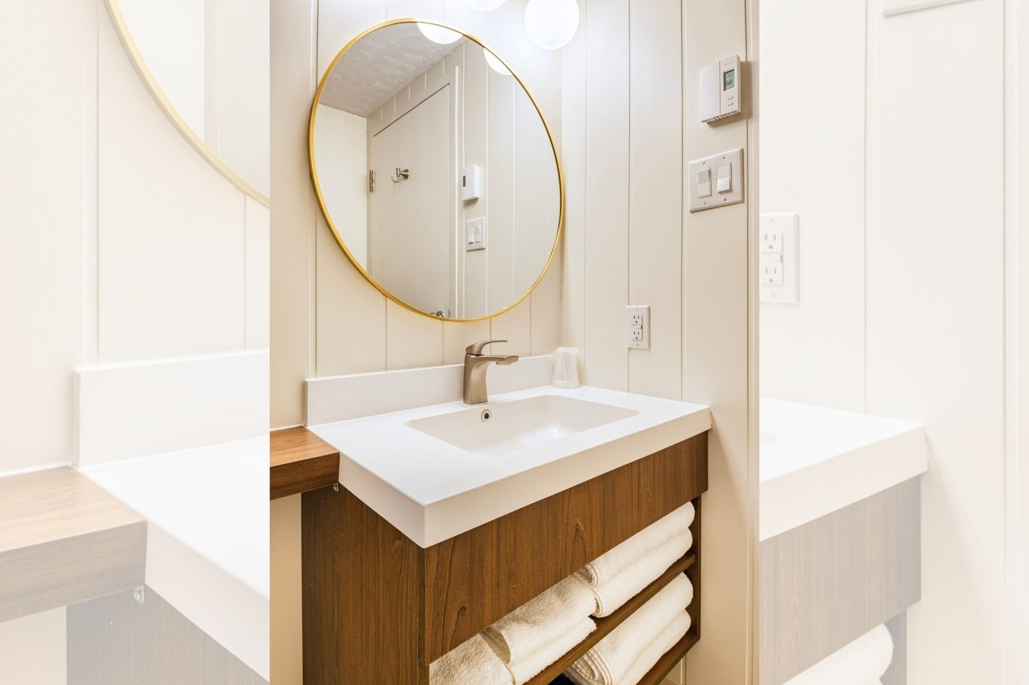 Une salle de bain moderne avec un lavabo blanc, un meuble-lavabo en bois et un miroir rond.