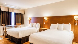Une chambre d’hôtel avec deux lits, un bureau et une chaise.