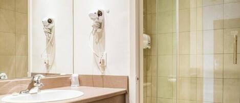 A modern bathroom with a large mirror, a sink, a toilet, and a glass-enclosed shower.