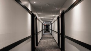 Un long couloir étroit, dont le sol est recouvert de moquette et dont les murs sont bordés de portes.