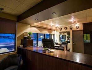 A hotel reception area with a reception desk, computer, and seating area. - Motel Mistral (Rouyn-Noranda)