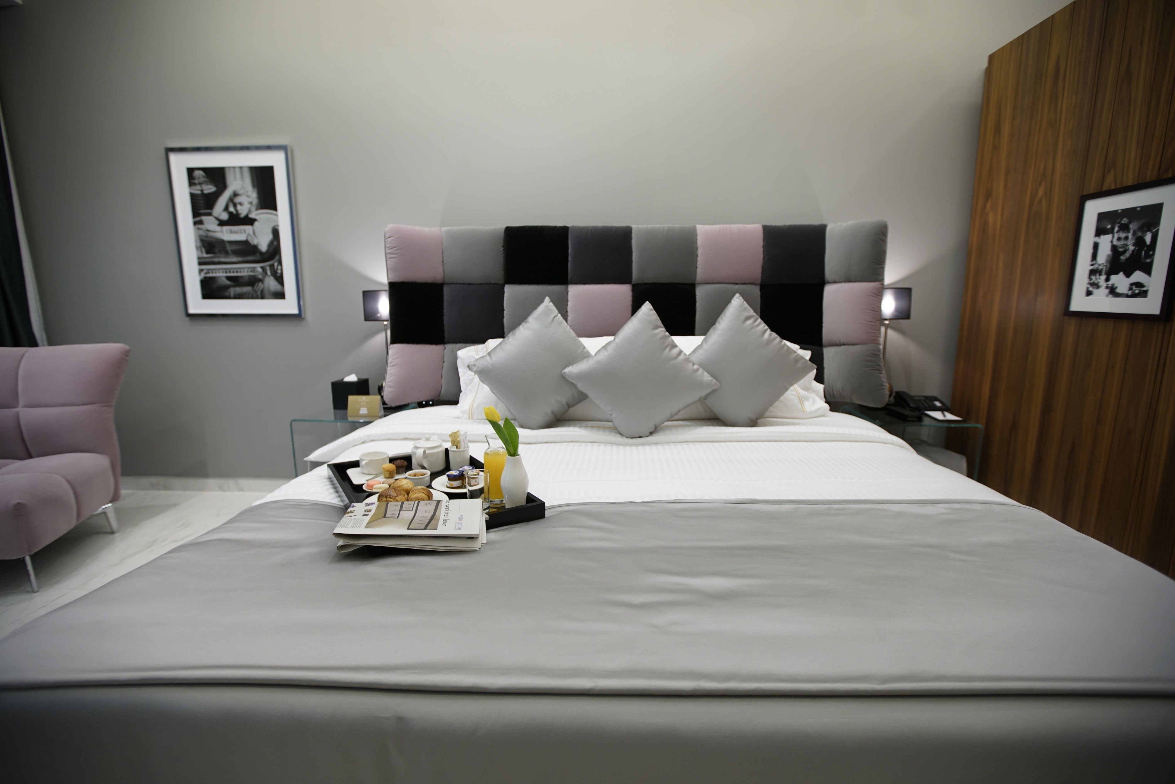 Ein modernes Hotelzimmer mit einem großen Bett, einem Nachttisch mit Lampe, einem Sessel und gerahmten Bildern an den Wänden.