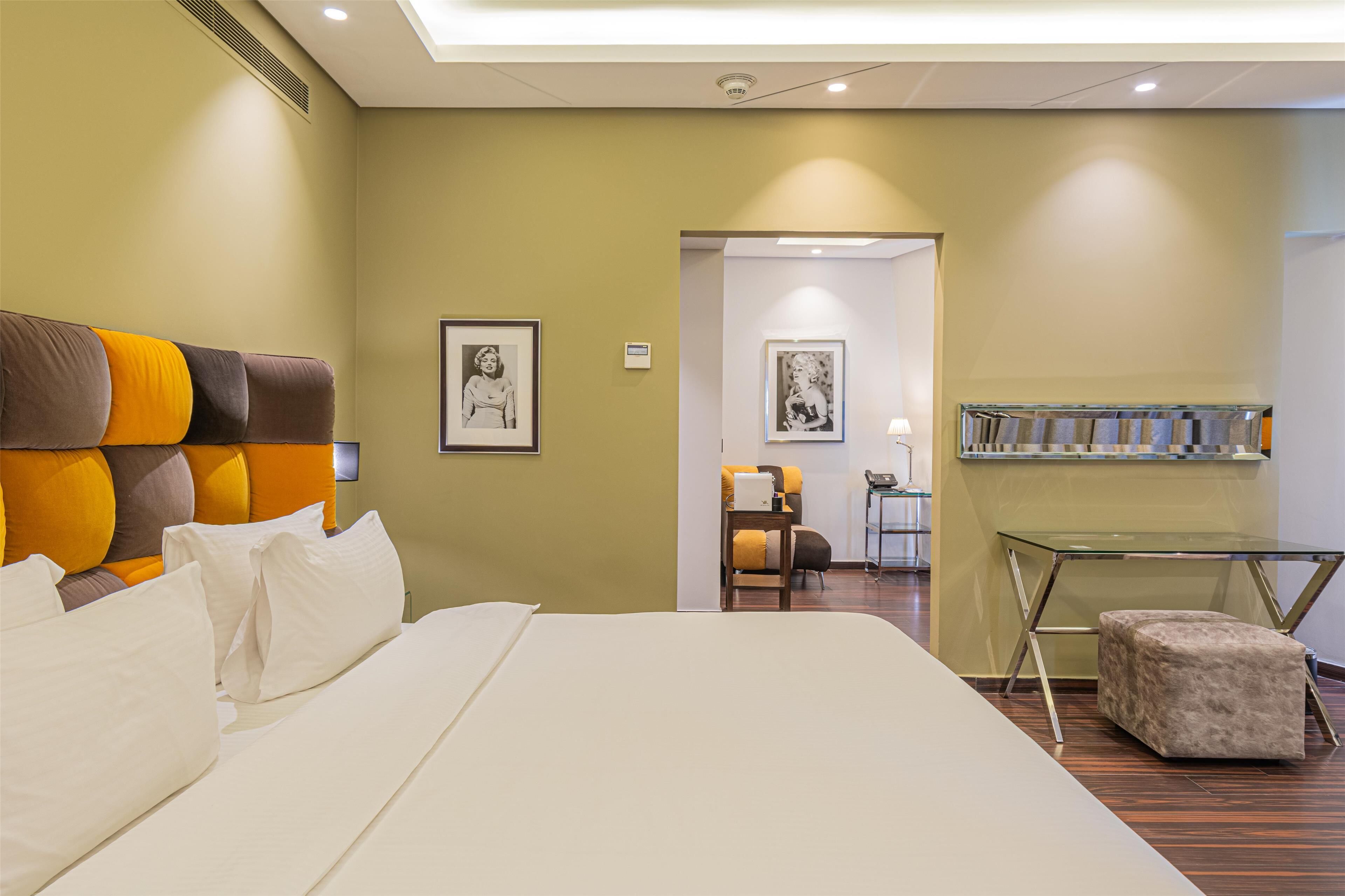 A hotel room with a large bed, a desk, and a chair.