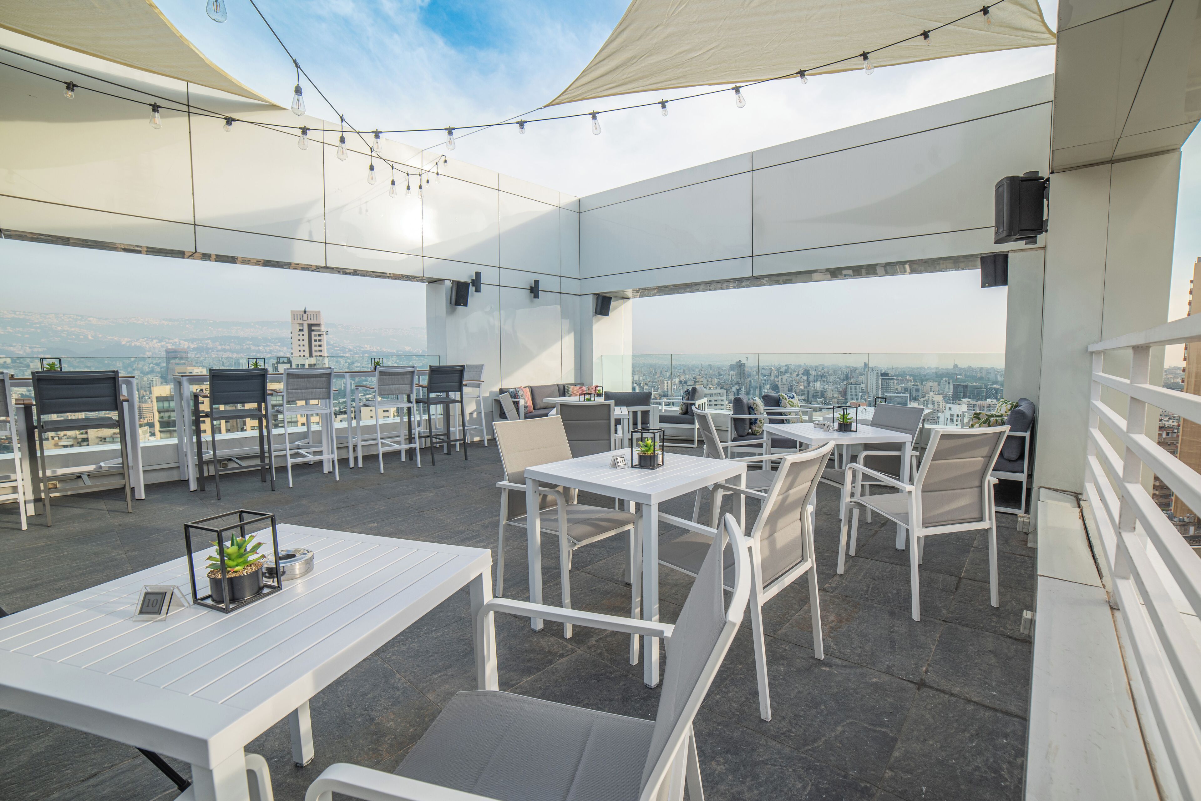 An outdoor terrace with tables and chairs, offering a city view.