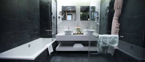 Une salle de bain moderne avec une douche à parois de verre, une baignoire blanche et un meuble-lavabo doté de deux vasques.