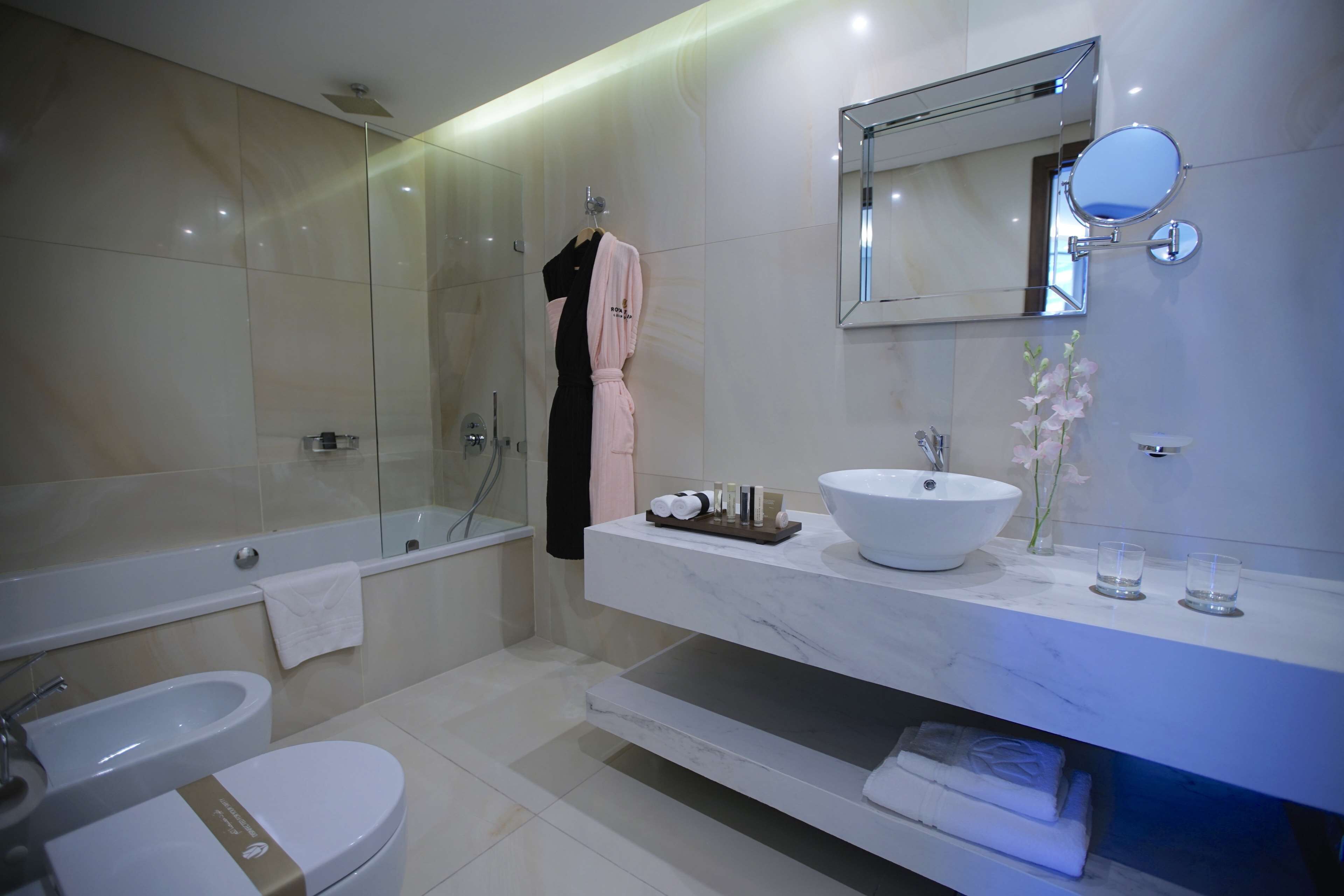 Un baño moderno con bañera, inodoro y tocador con un espejo grande.
