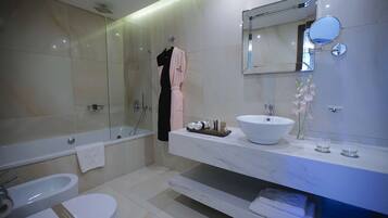Un baño moderno con bañera, inodoro y tocador con un espejo grande.