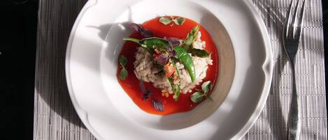 A white plate with a dish of rice and vegetables, garnished with red sauce and herbs, on a textured placemat.