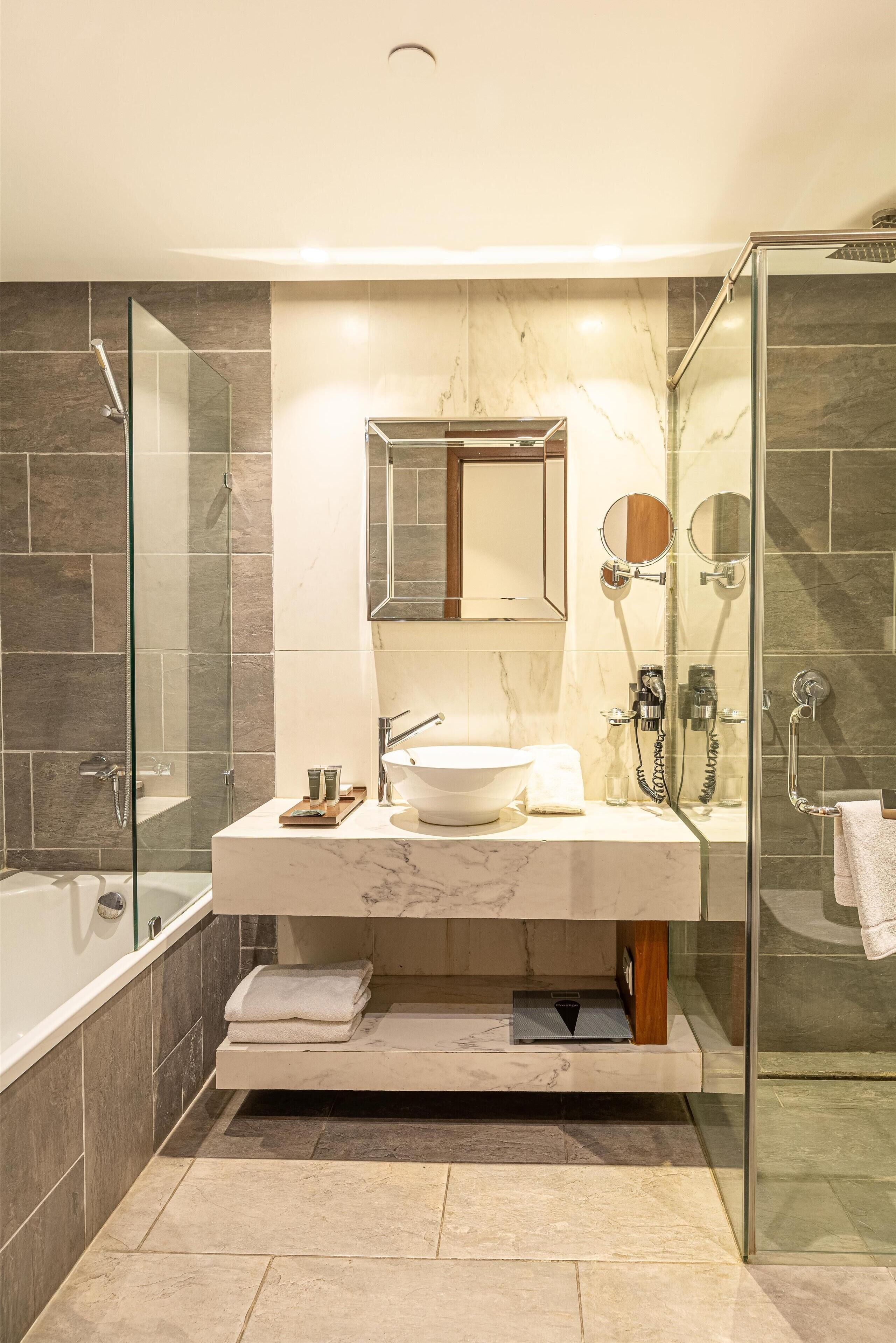 Une salle de bain moderne avec une douche à parois de verre, un lavabo en marbre et un grand miroir.