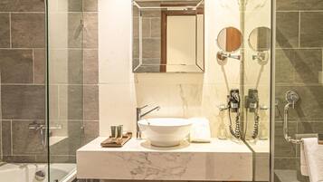 Une salle de bain moderne avec une douche à parois de verre, un lavabo en marbre et un grand miroir.