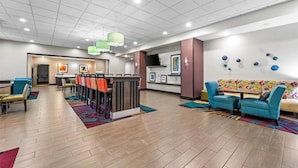 A hotel lobby with a reception desk, seating area, and a wall with framed pictures. - Hampton Inn Pratt (Pratt)