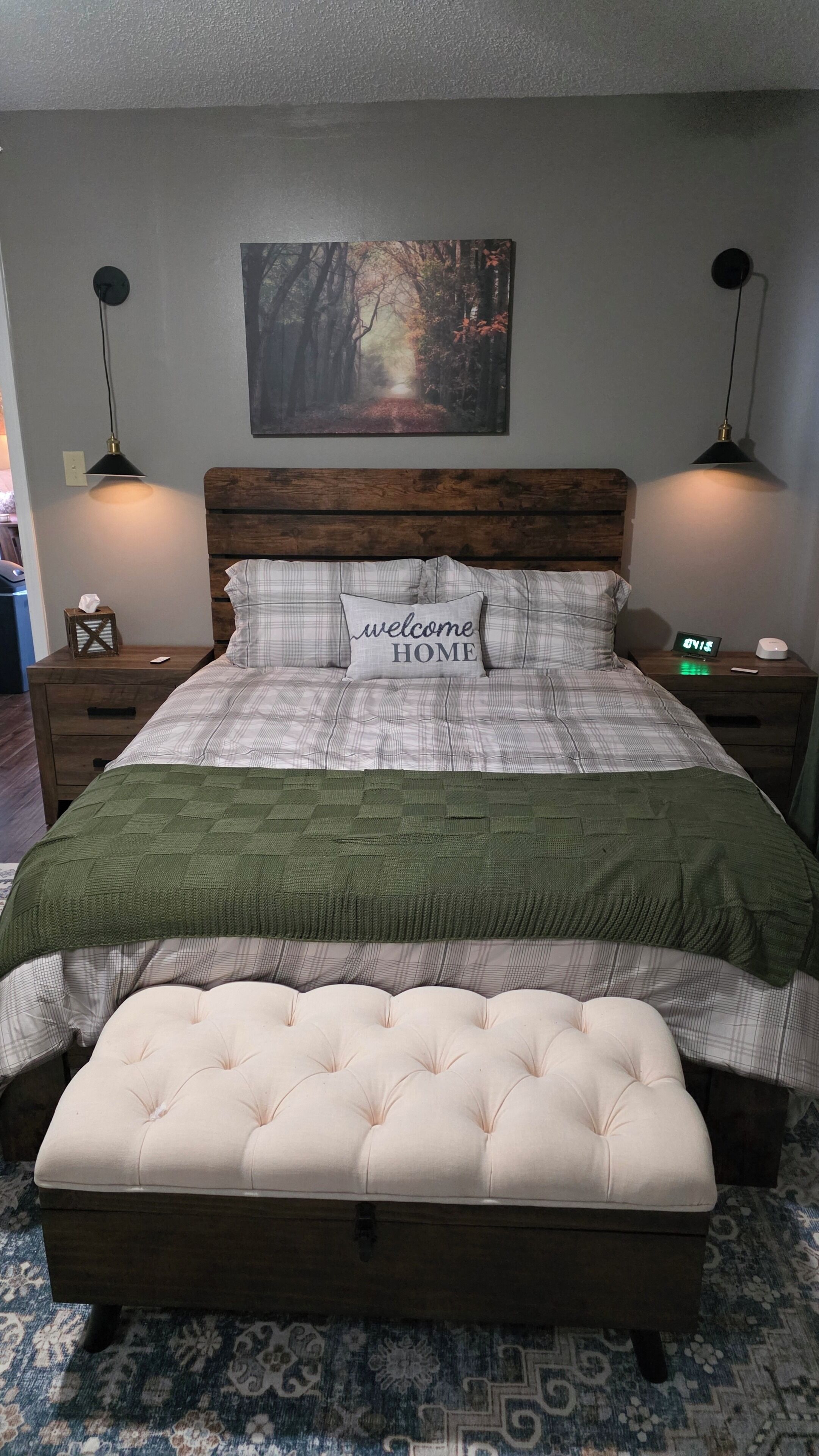 A bedroom with a bed, a bench, a nightstand, a wall clock, and a painting.