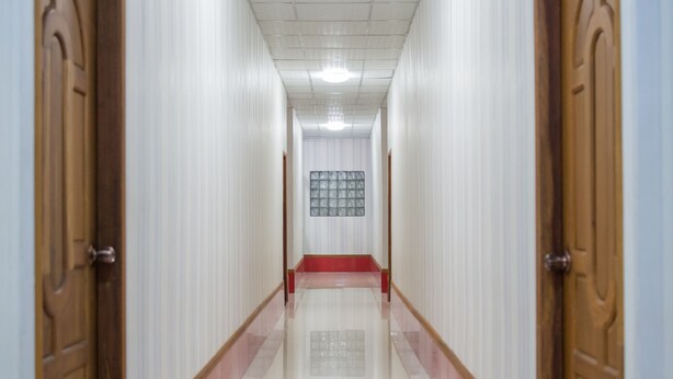 A long, narrow hallway with white walls and wooden doors on either side. - Aung Tha Pyay Hotel 2 (Yangon)