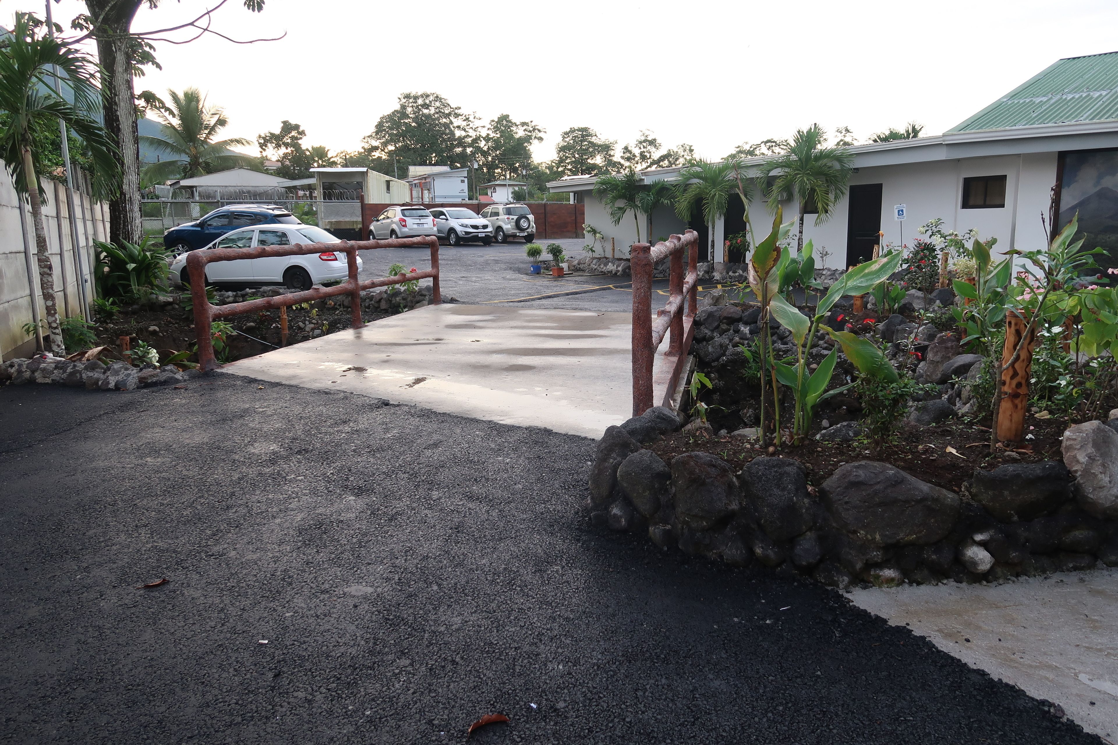 A gated parking area with a concrete pathway leading to a building.