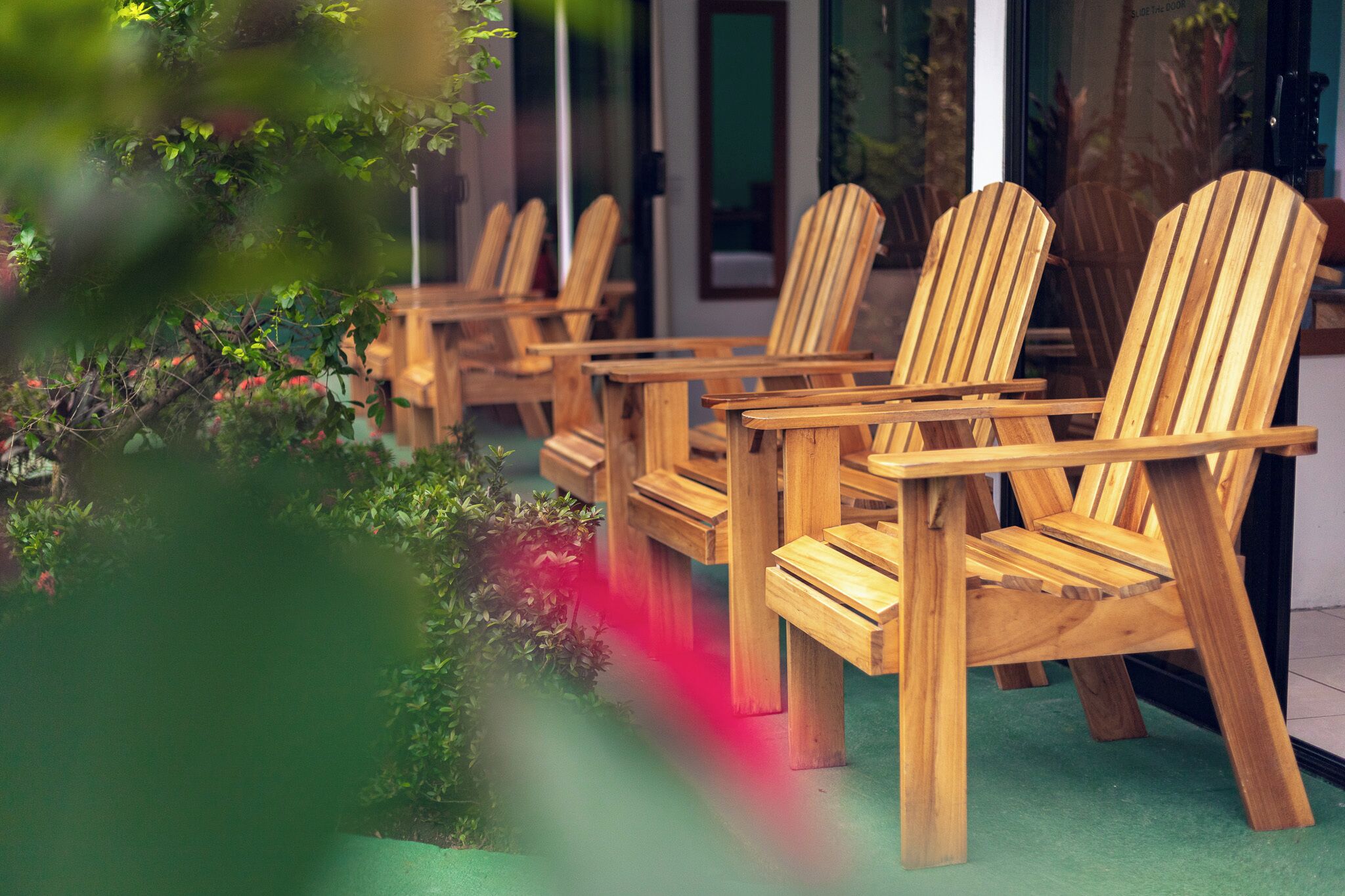 Des chaises en bois sont disposées à l’extérieur d’un bâtiment, sur un sol vert.