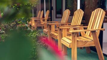 Wooden chairs arranged outside a building with a green floor.