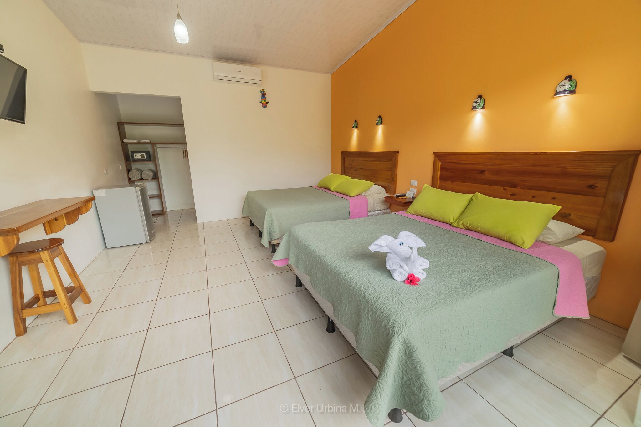 Habitación de hotel con dos camas, un escritorio y una kitchenette pequeña.