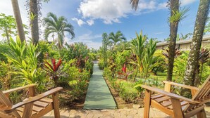 A garden pathway with two wooden chairs on either side, leading to a building. - Hotel Secreto La Fortuna (La Fortuna)
