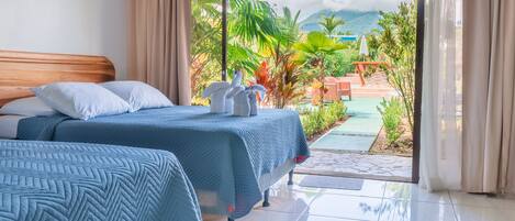 Une chambre d’hôtel avec deux lits, une grande fenêtre et une vue sur un jardin et des montagnes.