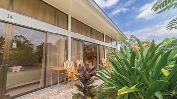 Un edificio moderno con amplios ventanales de vidrio, mobiliario exterior y un jardín bien cuidado.