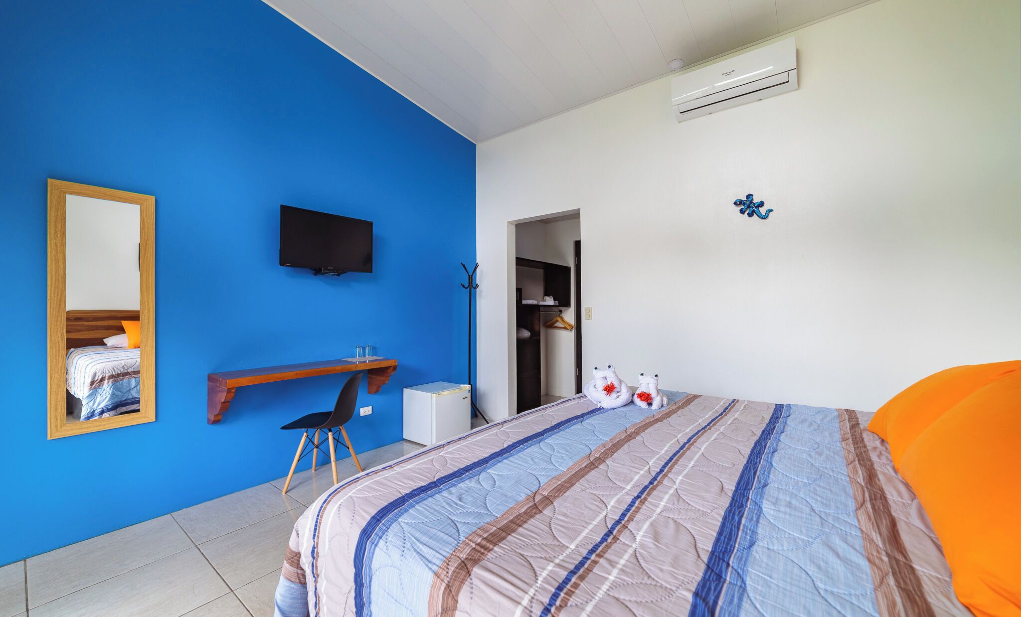 A bedroom with a bed, a desk, a chair, a television, and a wardrobe.