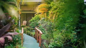 A garden pathway with wooden railings, surrounded by lush greenery and various plants. - Hotel Secreto La Fortuna (La Fortuna)