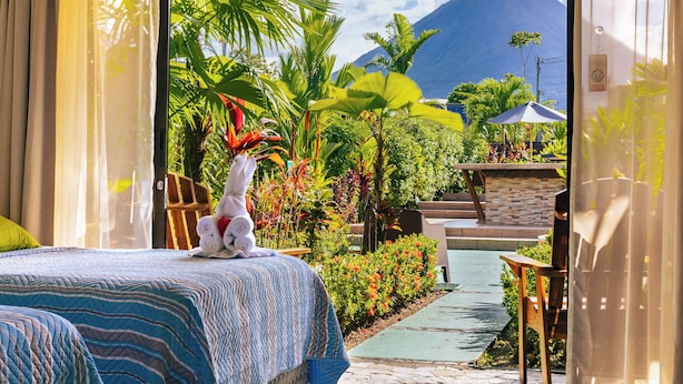 A hotel room with a bed, a view of a mountain, and a small pool area with plants and a chair. - Hotel Secreto La Fortuna (La Fortuna)