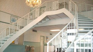 Una escalera con barandillas blancas ornamentadas y un candelabro.