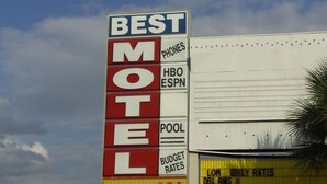 Letrero de motel que ofrece servicios como teléfonos, HBO, ESPN, piscina y tarifas económicas.