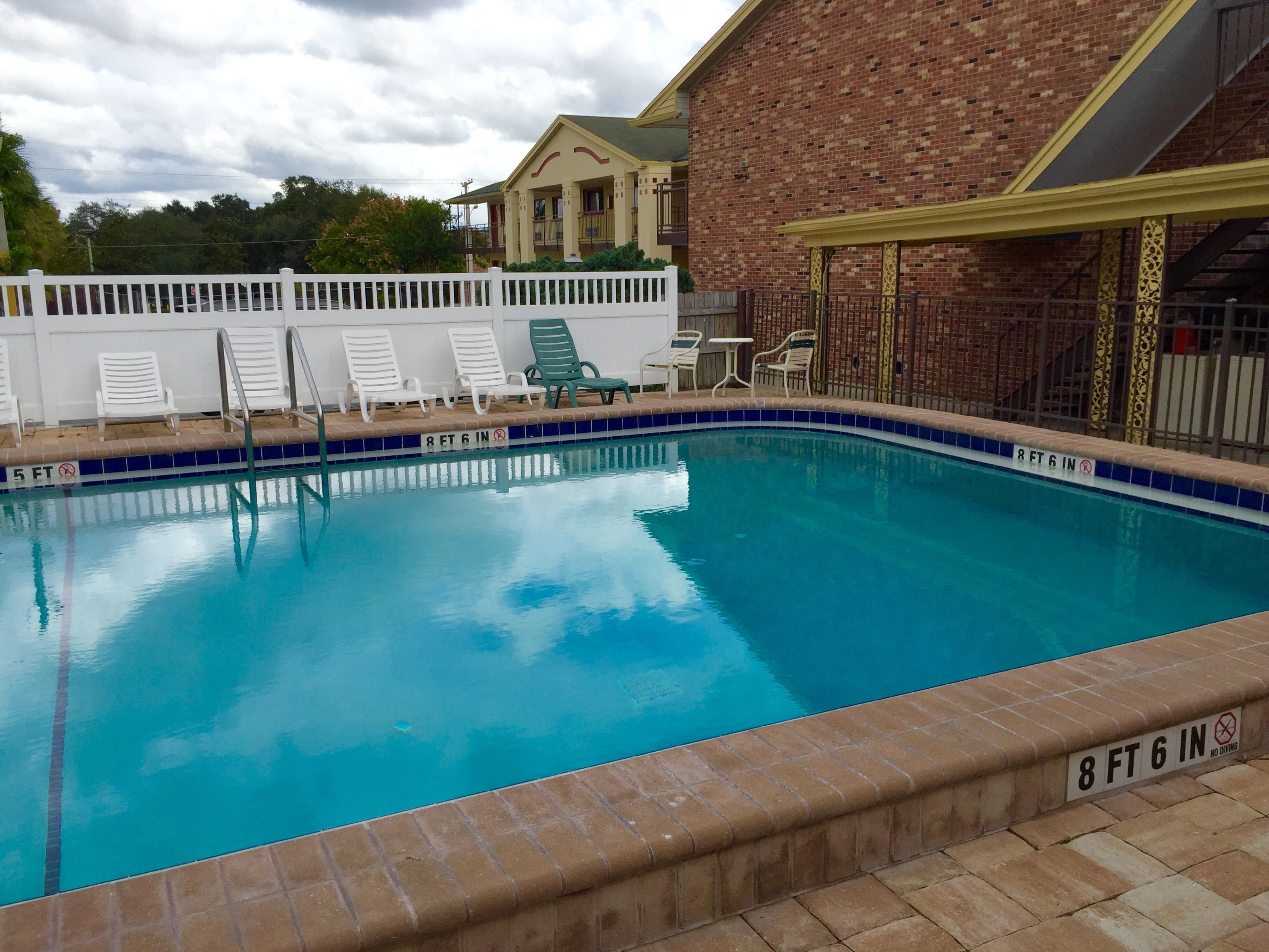 An indoor swimming pool with a 6-foot depth, surrounded by lounge chairs and a brick wall.
