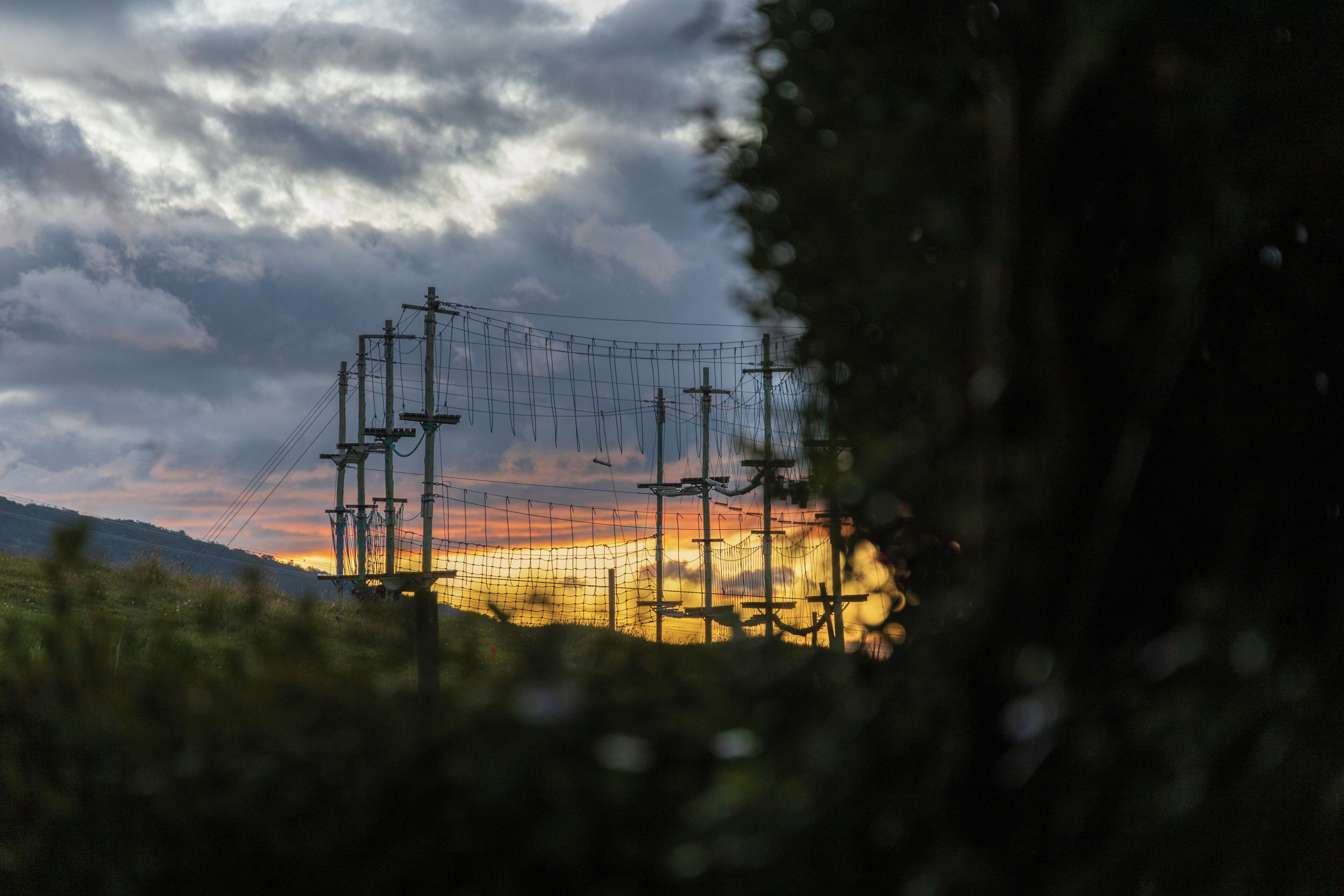 A power line structure with a sunset in the background.
