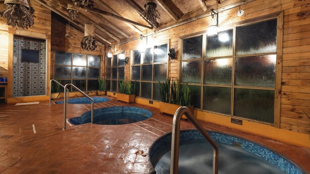 Un área de spa con varios jacuzzis, paredes de madera y amplios ventanales.
