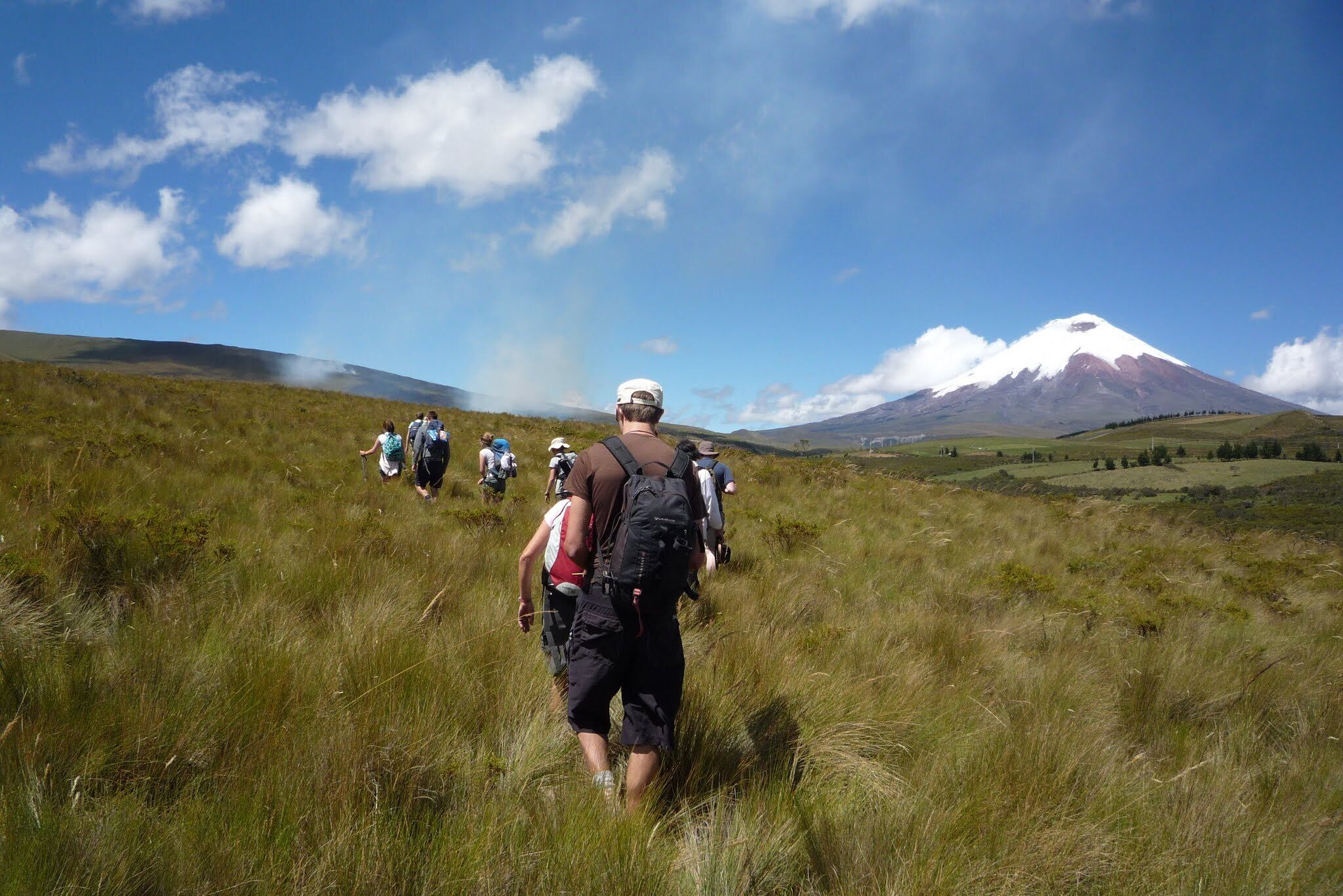 Un grupo de excursionistas en un campo cubierto de hierba con una montaña al fondo.