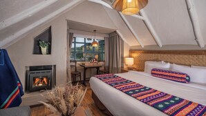 Una habitación acogedora con cama, chimenea, una mesa y ventana.