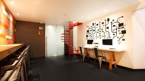 Un espacio de oficina moderno con un escritorio, dos sillas, una escalera espiral roja y una pared con gráficos abstractos.