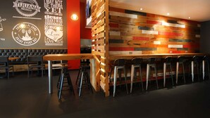 Zona de bar moderna con pared de listones de madera, taburetes y una pared de acento roja.