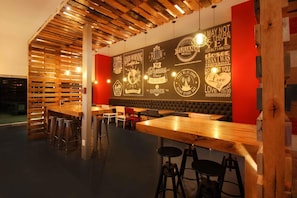 A café interior with wooden tables and stools, a red accent wall with motivational quotes, and a ceiling with exposed beams.